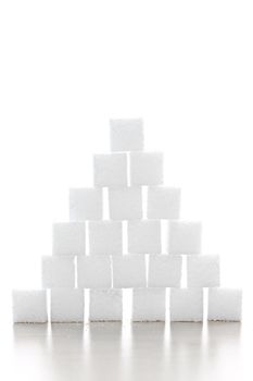 Pyramid of white sugar cubes stacked up on white background