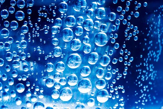 Bubbles in glass of water on a blue background