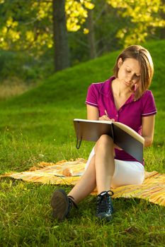 Beautiful woman writing in her diary in the park