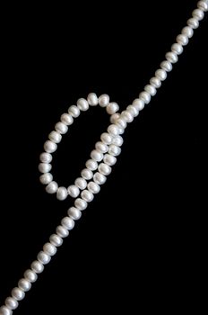 White pearls on the black silk as background 