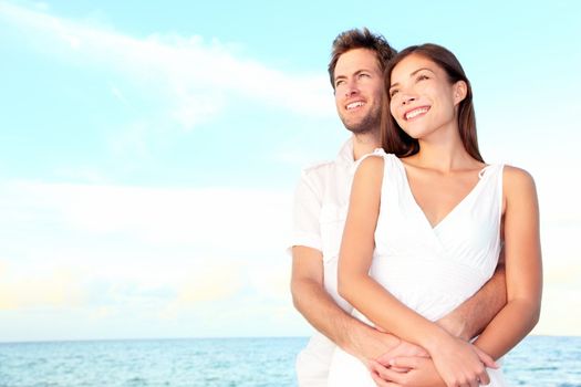 Happy beach couple portrait of beautiful young romantic interracial couple smiling happy embracing on beach during summer vacation. Caucasian man, Asian woman.