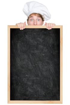 Funny chef showing blank empty blackboard menu sign for restaurant menu or recipe. Man chef cook or baker hiding behind chalkboard peeking over funny. Isolated on white background.