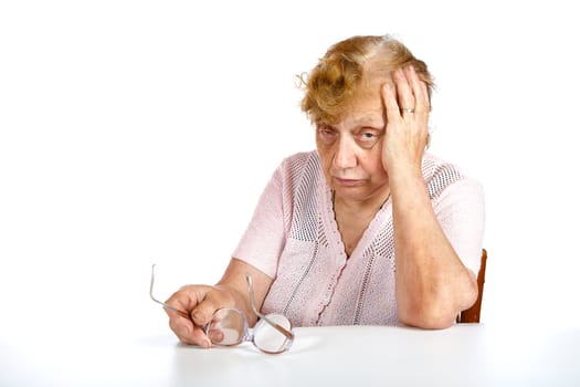 The thoughtful grandmother sits at  table isolated on a white background