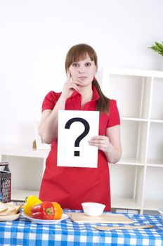 Young woman cooking fresh meal at home and holding question sign