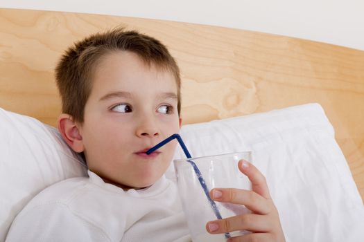 Seven years old drinking his milk in the bed.