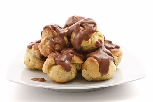 profiteroles with chocolate sauce over white background