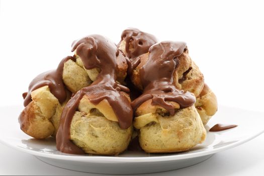 detail of profiteroles with chocolate sauce over white background