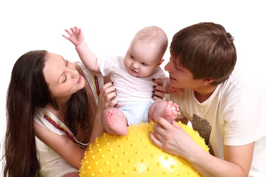 Portrait of a young family on a white background. The father, mum and the son. A horizontal format. The kid sits on a yellow ball, parents hold the kid