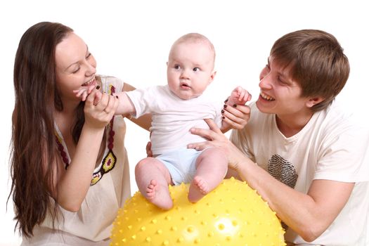 Portrait of a young family on a white background. The father, mum and the kid. A horizontal format. The kid sits on a yellow ball, parents look at the kid