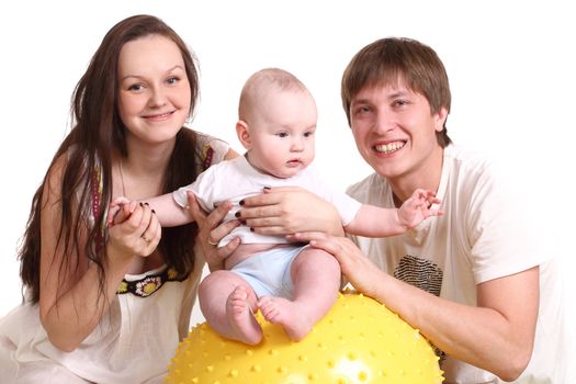 Portrait of a young family on a white background. The father, mum and the kid. A horisontal format. The kid sits on a yellow ball