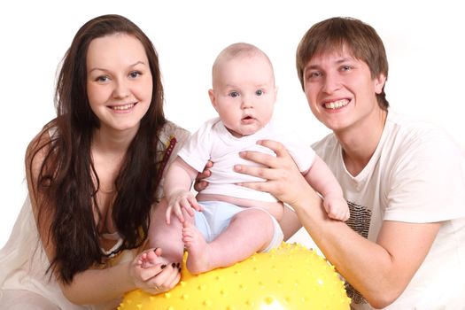Portrait of a young family on a white background. The father, mum and the kid. A horizontal. The kid sits on a yellow ball