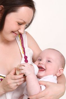 Young mum feeds from a small bottle of the small son, the kid smiles
