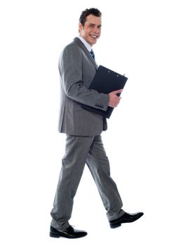 Handsome young businessman with notepad and pen, walking pose