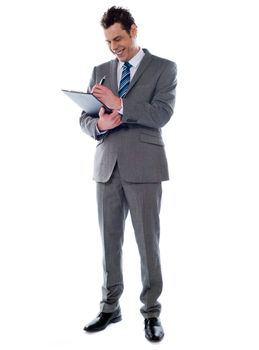 Portrait of a successful businessman writing notes on clipboard isolated on white background