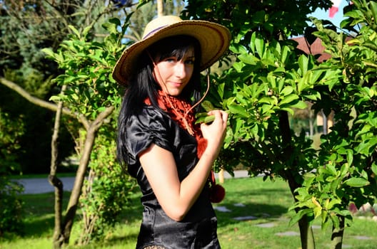 The photograph was taken in the park, shows a young attractive girl in a straw hat.