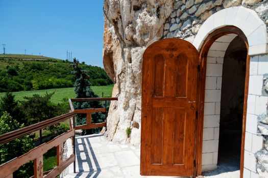 Orthodox monastery excavated in the rocks with open wooden door