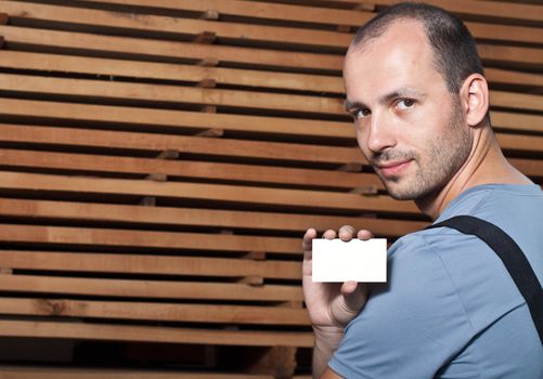Craftsman holding a business card on a wooden background.
