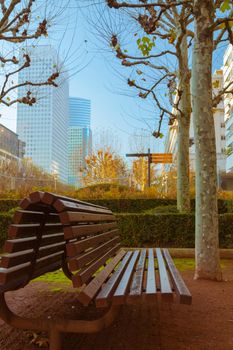 Vacant bench in a business area with skyscrapers and blue sky in the background