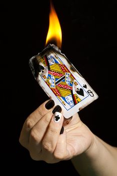 The queen of clubs is burning the queen of spades.