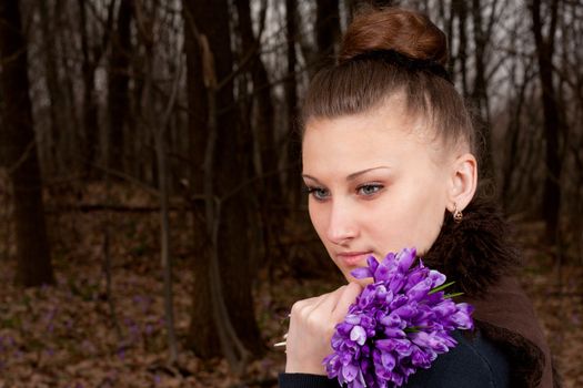 beautiful girl with snowdrops in a forest