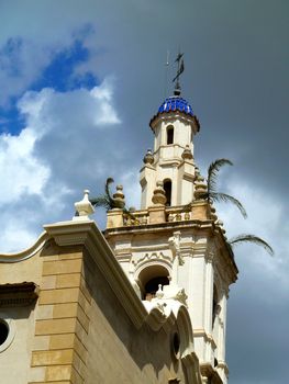 church spire with palm fronds against cloudy sky