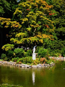 A photograph of a statue at a lake in a public park.