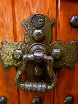 A photograph of a metal knocker on a wooden door.