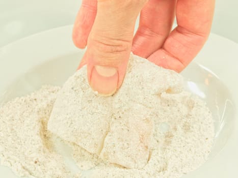 Person adding seasoning to a white fish fillet