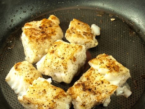 Someone frying seasoned white fish in a frying pan