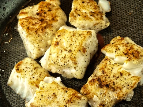 Someone frying seasoned white fish in a frying pan