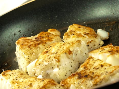 Someone frying seasoned white fish in a frying pan