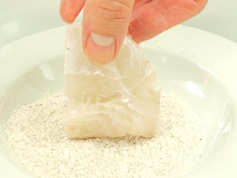 Person adding seasoning to a white fish fillet