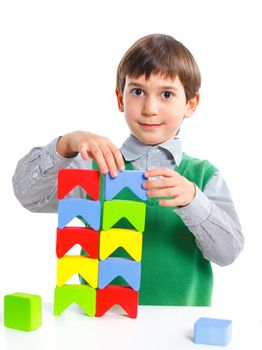 A smiling little boy is building a toy block. Isolated on white background