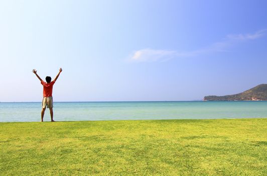 happy man on the meadow against the sea landscape