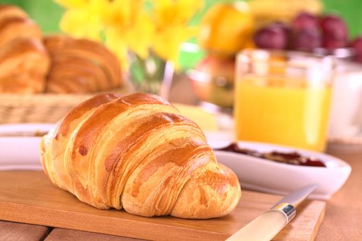 Croissant, jam, fruits and orange juice for breakfast (Selective Focus, Focus on the front of the croissant)