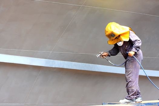 worker painting ship hull using airbrush