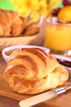 Croissant, jam, fruits and orange juice for breakfast (Selective Focus, Focus one third into the croissant)