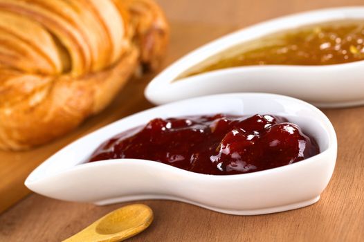 Strawberry and orange jam with croissant (Selective Focus, Focus on the front of the strawberry jam on the right side of the image)