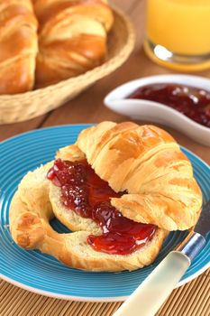 Croissant with butter and strawberry jam (Selective Focus, Focus on the front of the strawberry jam)