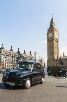 LONDON, UK - APRIL 02: Famous black cab driving by Houses of Parliament, with Big Ben prominent in the picture. April 02, 2012 in London.