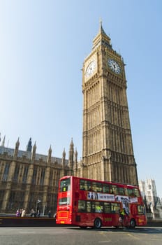 LONDON, UK - APRIL 02: Famous red double-decker bus driving by Houses of Parliament, with Big Ben prominent in the picture. April 02, 2012 in London.