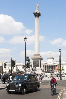 LONDON, UK - APRIL 02: Famous black cab driving by Trafalgar Square, with Nelsons Column in the background. April 02, 2012 in London.