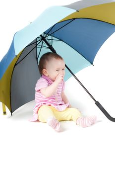 Shot of cute baby girl sitting uner umbrella