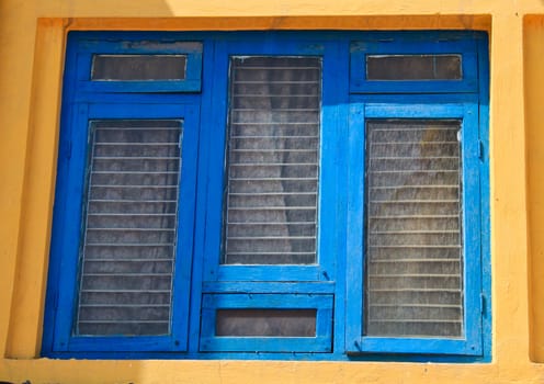 Blue wooden windows on yellow wall