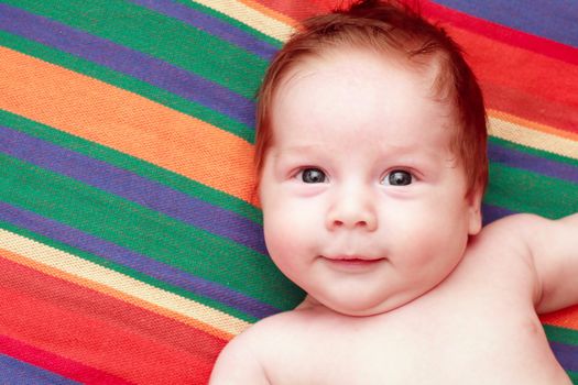 portrait of a smiling baby in a striped fabric