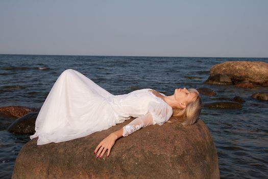Woman lying on rock at seaside