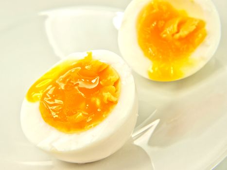 Soft boiled egg, isolated on white plate, in half