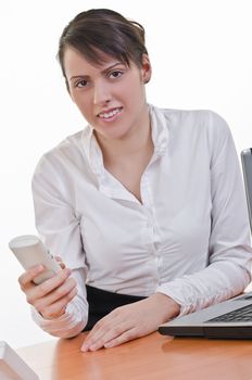 Portrait of a happy young woman holding phone in front of a laptop computer, high key, focus on eyes