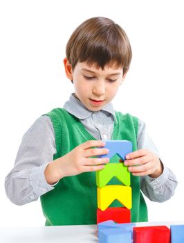 A smiling little boy is building a toy block. Isolated on white background