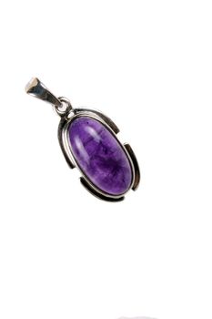 A beautiful silver pendant with an amethyst gemstone used as fashion accessory as well as an alternative healing method in astrology, isolated on white studio background.